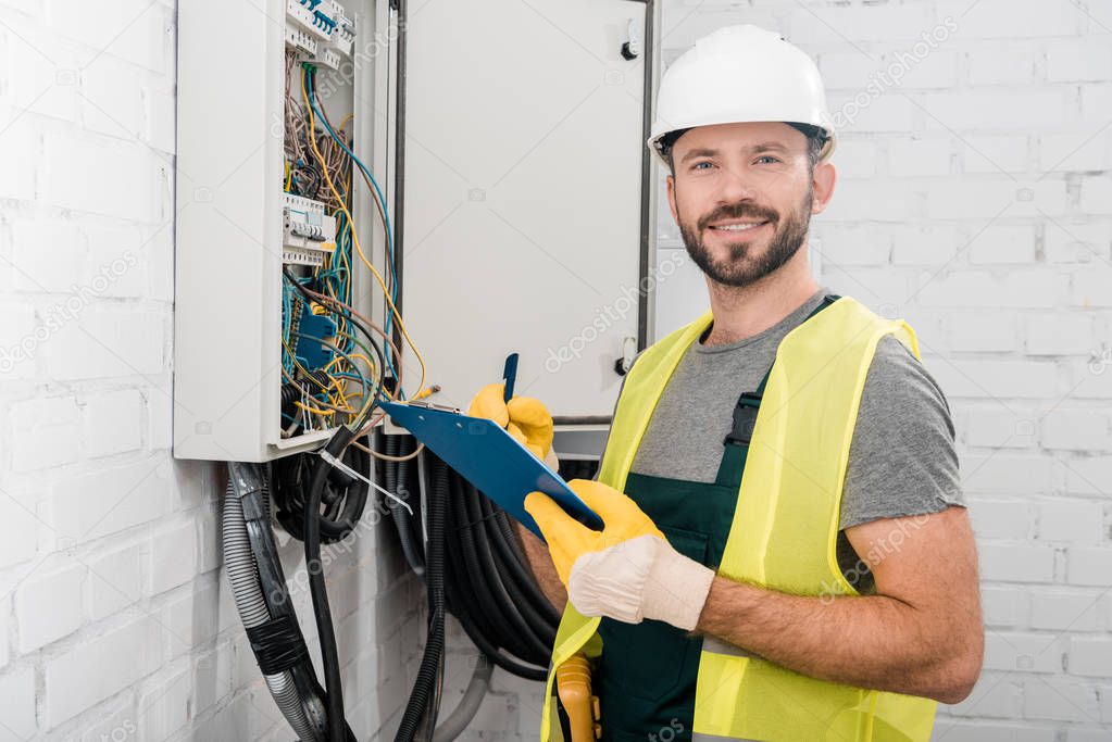 Técnico electricista con casco y herramientas trabajando en sitio